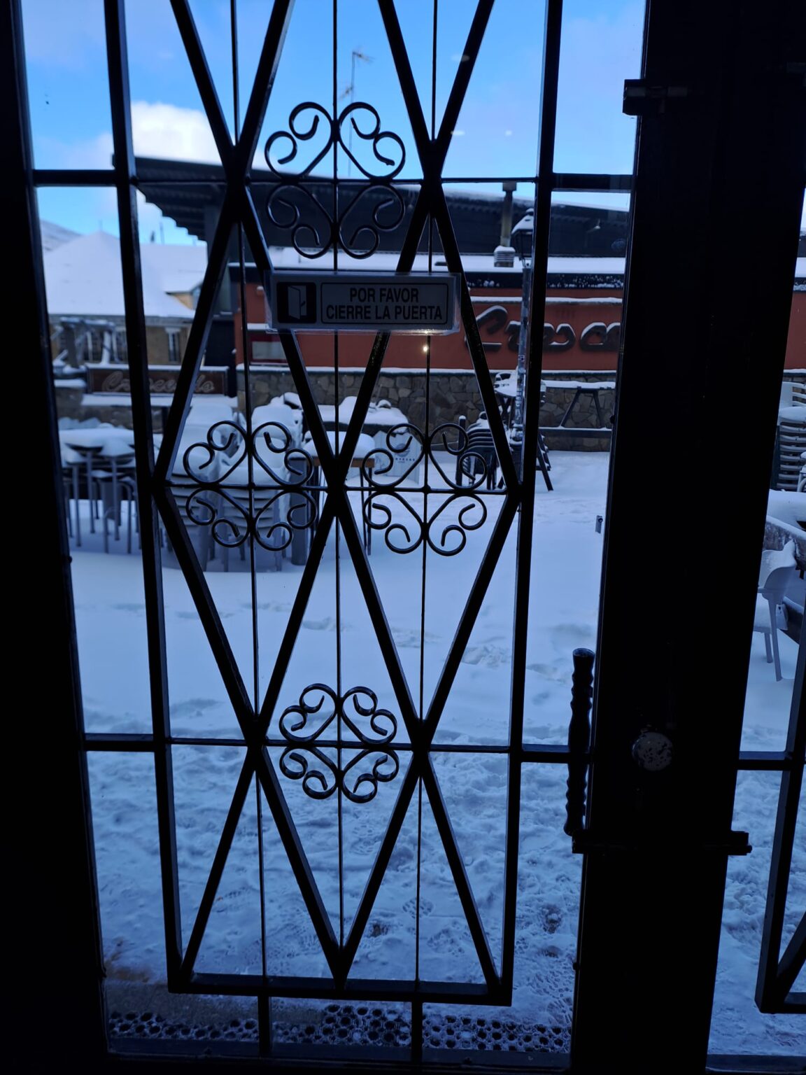 a una vista hacia el exterior de la calle entre el propio edifico impala y el telecabina borreguiles desde la puerta del portal